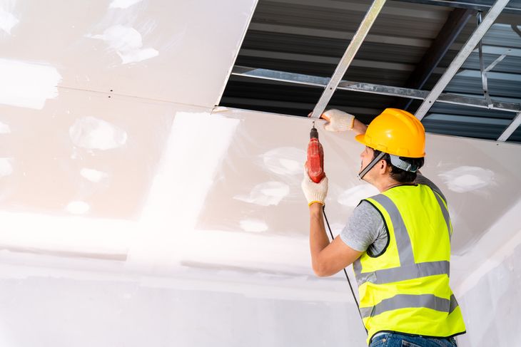 Construction workers using an electric drill are install the ceiling house in the building under construction, Ceiling installation ideas